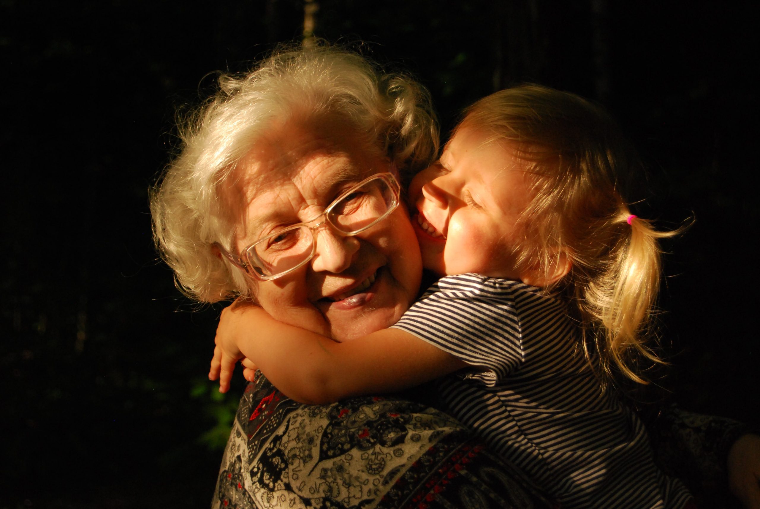 Abuela sonriente siendo besada por su nieta