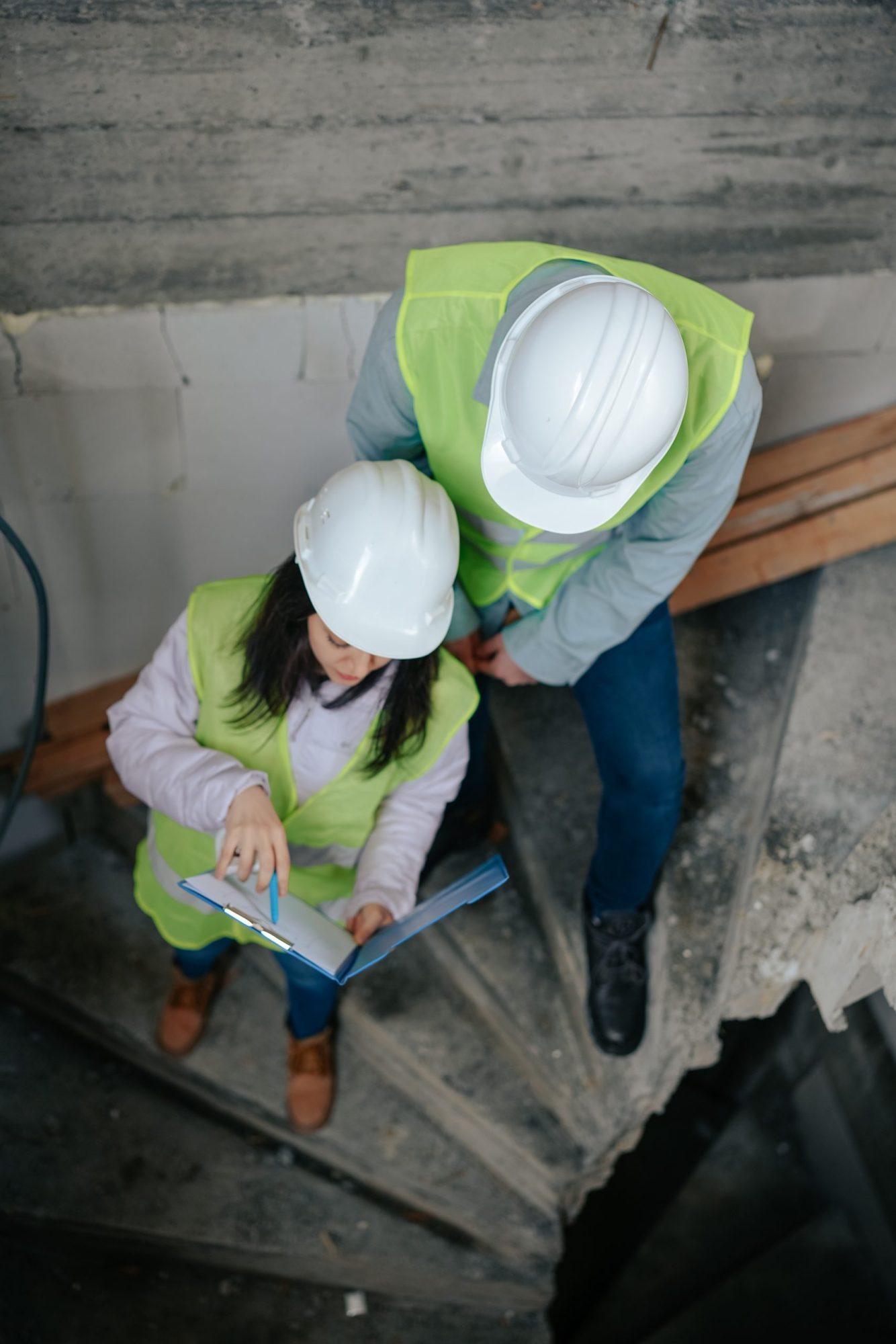 Dos personas con casco trabajando en una obra de escalera